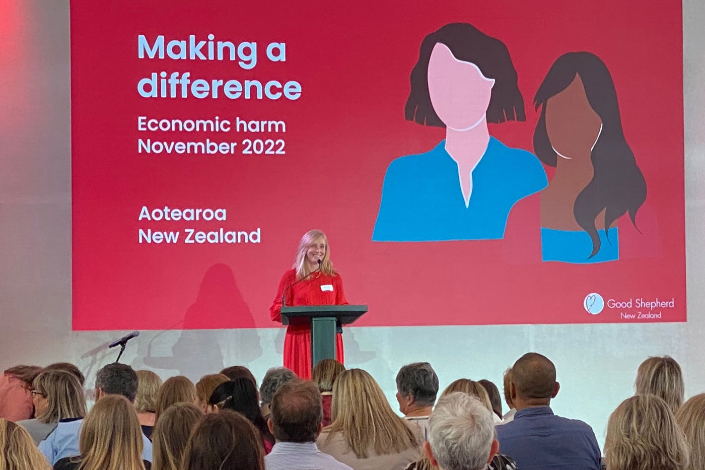 Woman smiling and presenting at a conference.